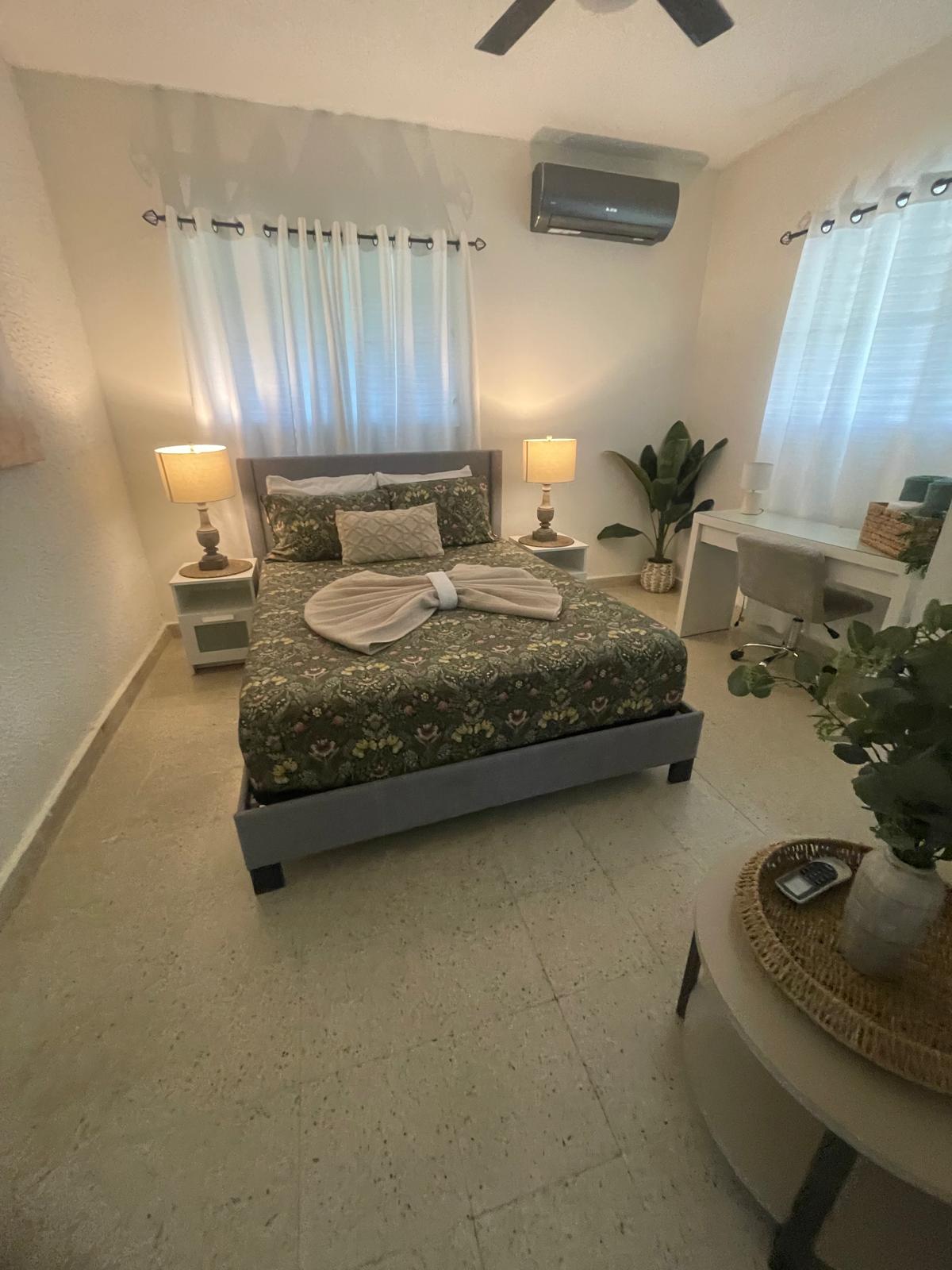 Habitación con cama tendida y área de escritorio tras limpieza de propiedad Airbnb en Puerto Rico